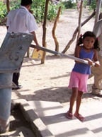 A little girl is getting water from a handpump
