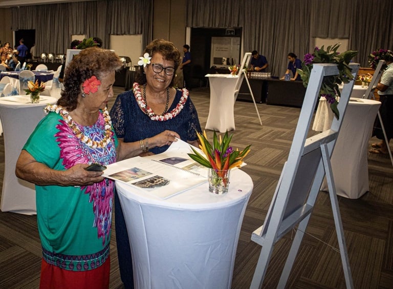 WHO retirees Mrs Lucy Penn and Mrs Perelini review their WHO Memory Book at the WHO 75th Anniversary celebration.
